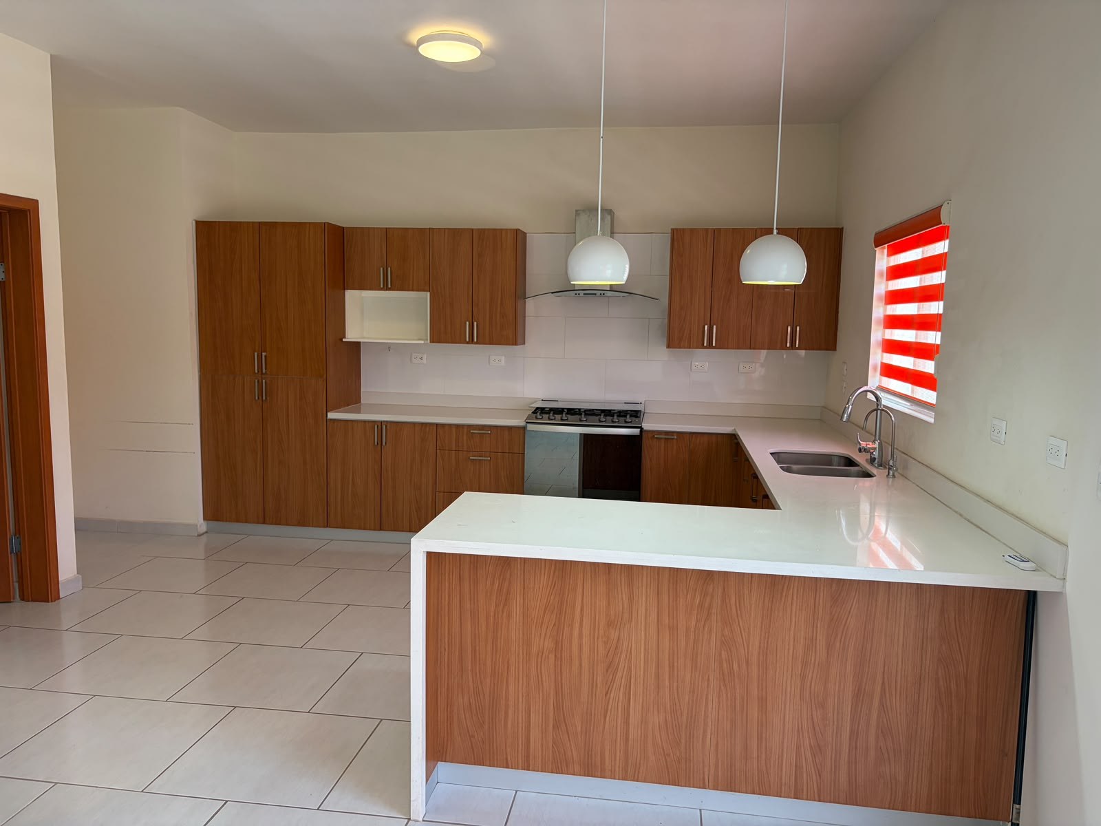 Cocina integral real con gabinetes de madera y barra blanca